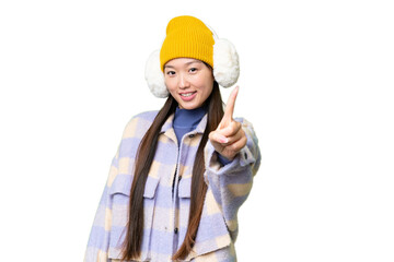 Young Asian woman wearing winter muffs over isolated chroma key background showing and lifting a finger
