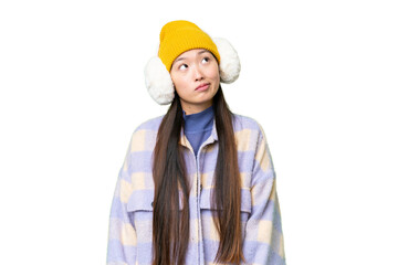Young Asian woman wearing winter muffs over isolated chroma key background and looking up