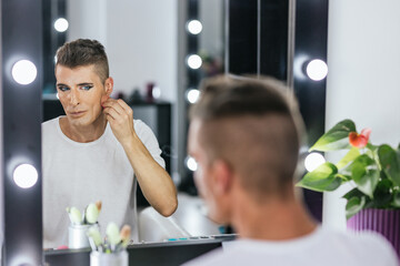 Gay man using mascara to make up in backstage