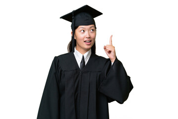 Young university graduate Asian woman over isolated background pointing up and surprised