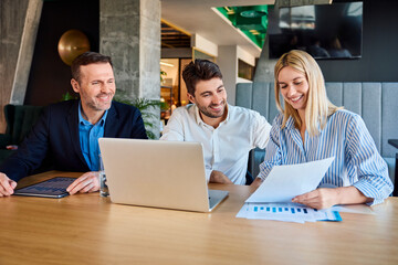 Smiling business people analyzing graphs and data at desk