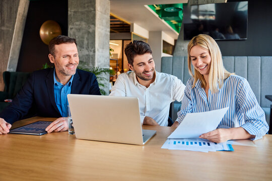 Smiling business people analyzing graphs and data at desk