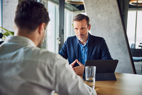 Serious recruiter taking interview of candidate at desk