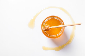 Jar with tasty natural honey and dipper on white background, top view