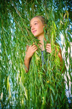 Girl standing amidst leaves of willow tree