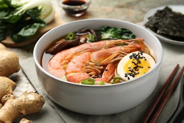 Delicious ramen with shrimps and egg in bowl served on table, closeup. Noodle soup