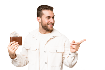 Young handsome blonde man holding a wallet over isolated chroma key background pointing to the side to present a product