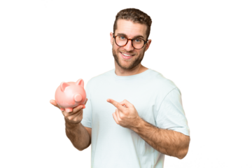Young man holding a piggybank over isolated chroma key background and pointing it