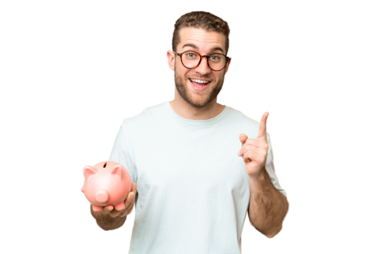 Young man holding a piggybank over isolated chroma key background pointing up a great idea