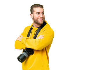 Young photographer man over isolated chroma key background with arms crossed and happy