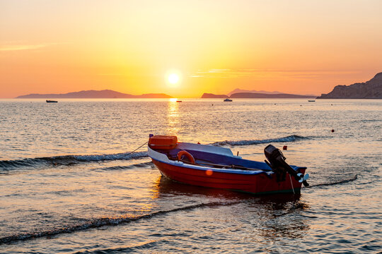 Greece, Ionian Islands, Arillas, Motorboat left on beach at sunset