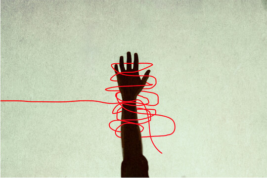 Human hand trapped in red tangled strings