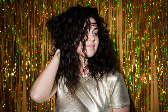 Woman with hand in hair standing near tinsel curtain