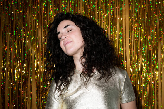 Woman with eyes closed in front of tinsel curtain