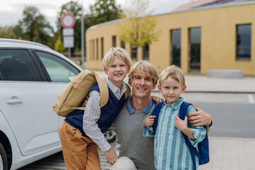 Father saying goodbyeto to sons in front of school building. Dad heading to work. Concept of...