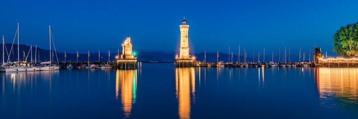 Germany, Bavaria, Lindau, Harbor of town on shore of lake Bodensee at night with lighthouse andBavarian Lion sculpture in background