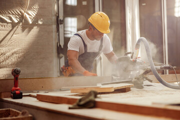 Male worker using wood cutting circular saw machine in workshop