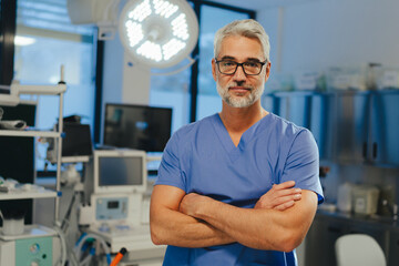 Portrait of confident ER doctor standing in hospital emergency room. Handsome doctor in scrubs...