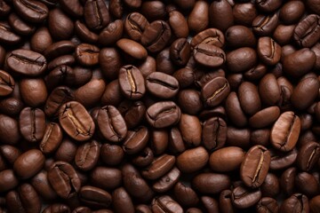 Fototapeta premium Close up view of dark fresh roasted coffee beans on coffee beans background. Closeup of coffee beans scattered background