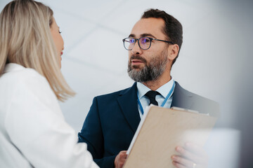 Pharmaceutical sales representative talking with female doctor in medical building. Hospital...