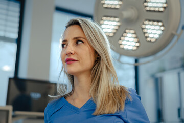 Portrait of ER doctor in hospital working in emergency room. Portrait of beautiful nurse in blue uniform, low angle shot.