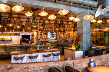 Interior of cozy modern restaurant with a bar counter and lamp lighting