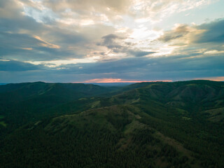 Beautiful summer landscape, mountains and green forest with pine trees against the sky with clouds at sunset in the evening. Nature background with copy space. Photos from the drone.