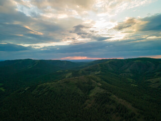 Fototapeta premium Beautiful summer landscape, mountains and green forest with pine trees against the sky with clouds at sunset in the evening. Nature background with copy space. Photos from the drone.