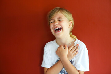 Pretty emothional child on a red background. Copy space, daylight