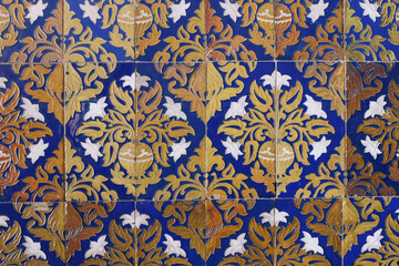 Detail of vintage Spanish ceramic tiles.Baroque styled pattern with lilies flowers, vases. Old blue azulejo facade with floral ornaments. Antique building detail. Artistic hand drawn decorative
