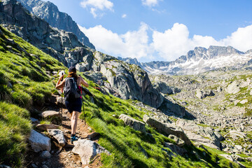 Young hiker girl summit to Ratera Peak in Aiguestortes and Sant Maurici National Park, Spain - obrazy, fototapety, plakaty