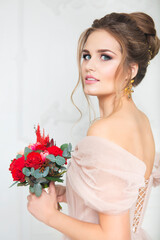 Young pretty bride with bridal bouquet indoors