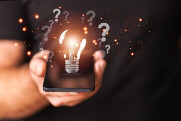 Businessman holding classic light bulb with question marks