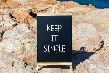 Keep it simple symbol. Concept word Keep it simple on beautiful black chalk blackboard. Beautiful stone beach sea blue background. Business motivational keep it simple concept. Copy space.