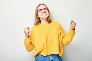 Portrait of smiling face girl clenching fists and rejoicing, celebrating victory isolated on white...