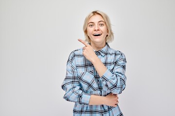 Young blond woman in casual pointing aside finger, demonstrating empty space for product or text...