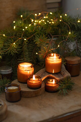 Soy candles burn in glass jars. Comfort at home. Candle in a brown jar. Scent and light. Scented handmade candle. Aroma therapy. Christmas tree and winter mood. Cozy home decor. Festive decoration.