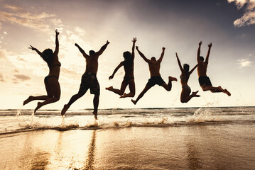 Group of silhouettes of happy young friends are having fun and jumps together at sunset sea beach - obrazy, fototapety, plakaty