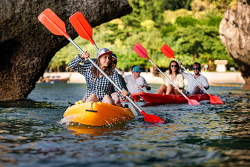 Big group of young friends are walks on kayaks or canoes at sea beach. Phranang beach, Krabi...