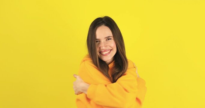 Come into my arms. Adorable happy girl with brown hair make gesturing come here for free hugs and smiling sincerely with welcoming expression isolated on yellow background. Come to me, hug self.