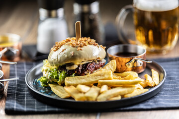 Beef burger topped with cheese with fries and draft beer on a pub or restaurant plate