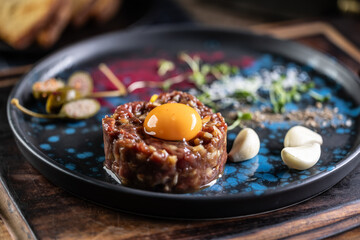 Beef tartare with egg yolk on a plate with garlic and toasted bread