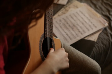 Close up, cinematic, young musician learns to play classical guitar at home.  Guitar , music notes....
