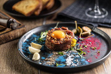 Beef tartare with egg yolk on a plate with garlic and toasted bread