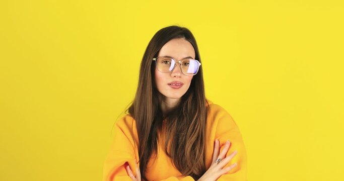 Lady boss. Close up portrait of young confident brunette hair woman putting on her eyeglasses, looking seriously at camera. Career and feminism concept. Eyesight problem isolated on yellow background.