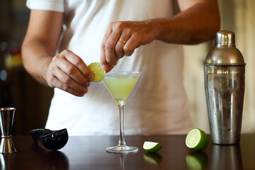 Barman at work, preparing cocktails. Pouring martini to cocktail glass
