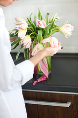 Woman arranging floral bouquet in a kitchen