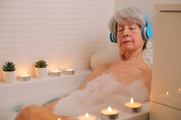 Senior woman closing her eyes in the bathtub while listening to music 