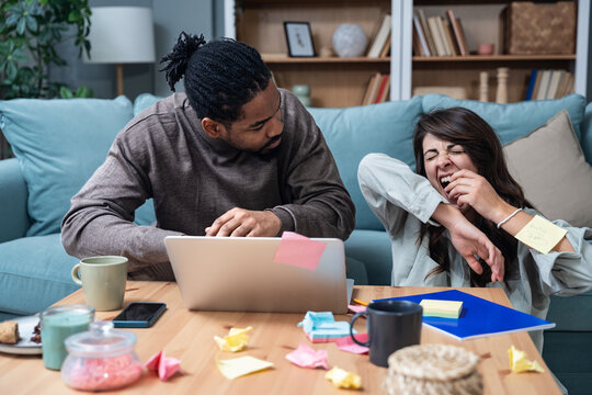 Young tired freelance couple small company owners, new business partners, work at home on product strategy for global business. Web developers research, interior designers creatives working late.