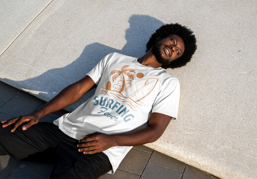 Mockup of man wearing customized t-shirt lying on ground